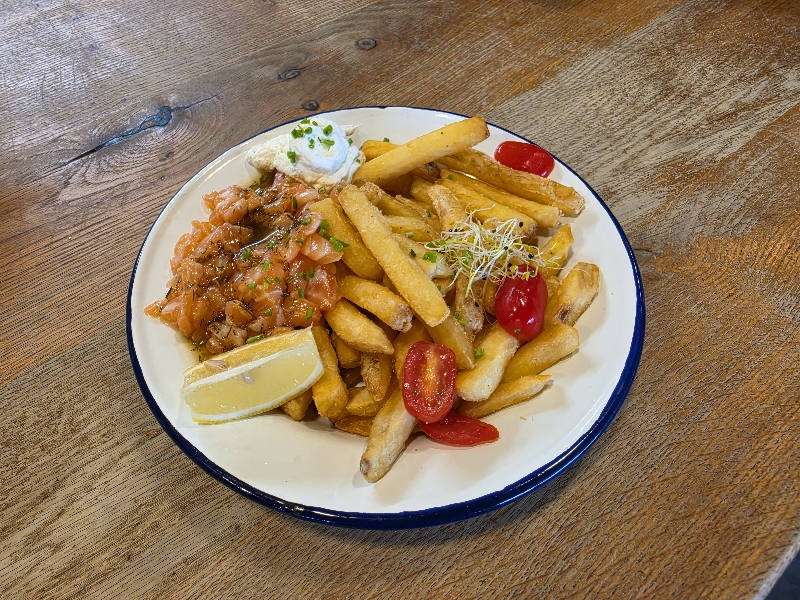 Tartare de saumon accompagné de frites, de citron et de tomates cerises